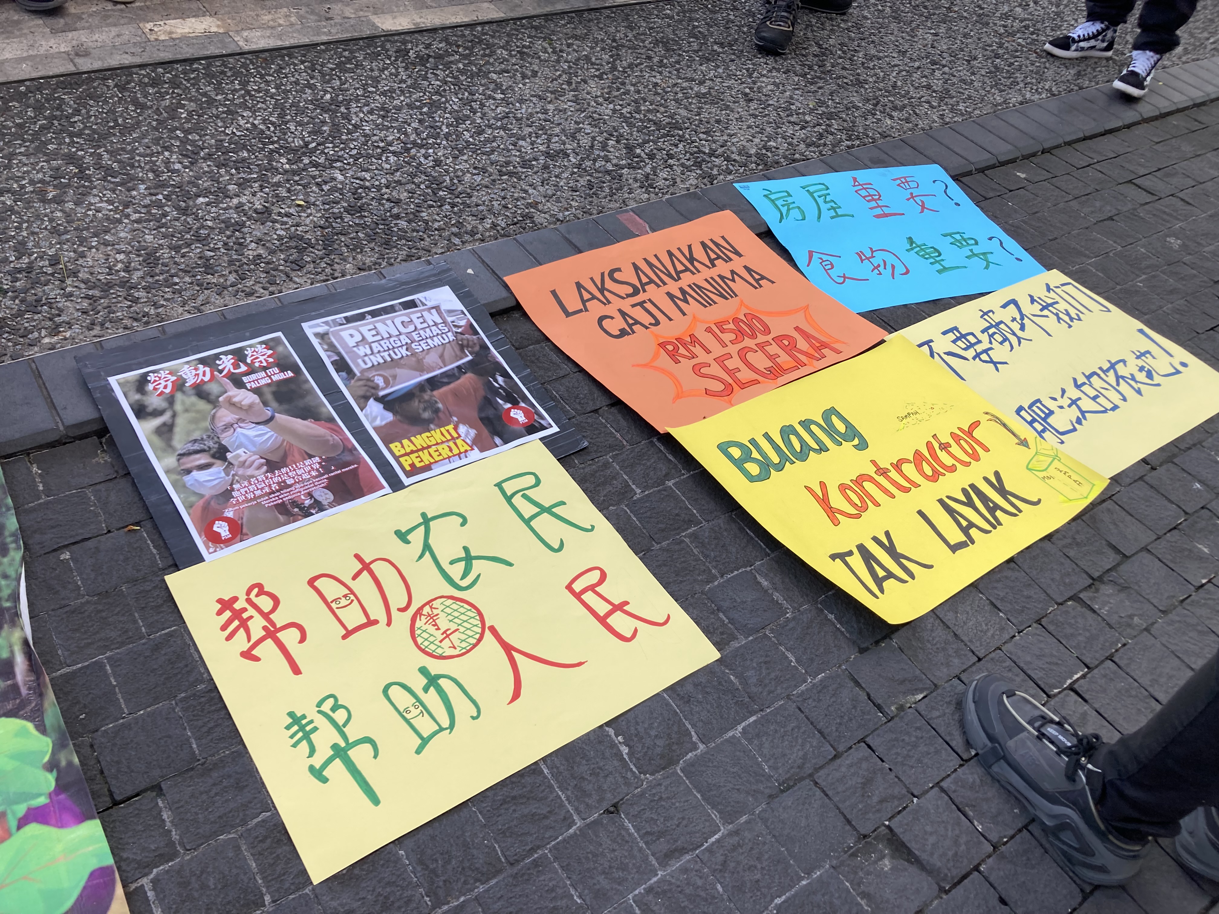 Handmade signs advocate in Chinese for the rights of rural workers, reading “Helping farmers equals helping the people” and “Is housing important? Is food important?” and “Don’t destroy our fertile farmland!” 
